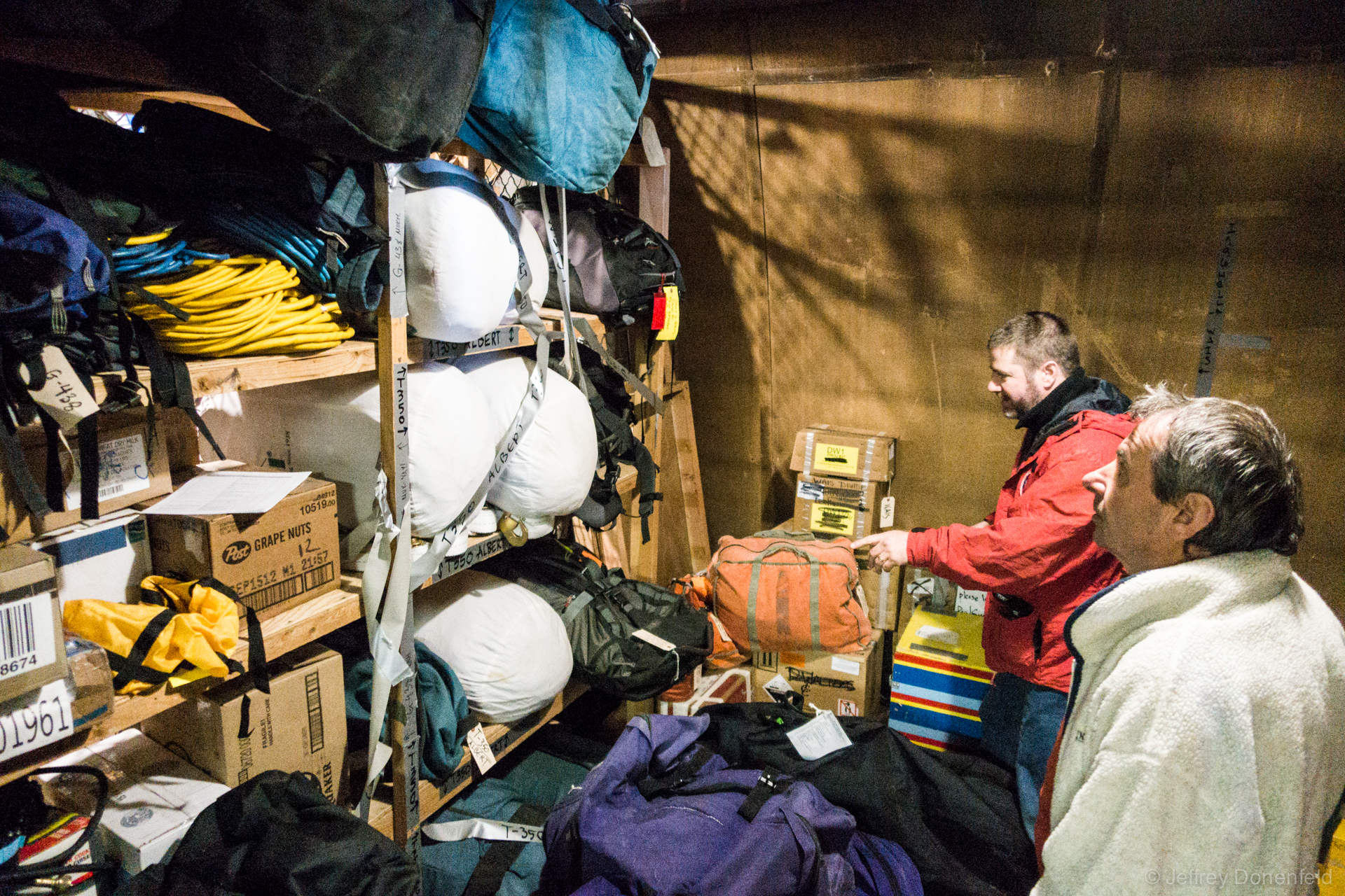 Going through our racks of gear in the cage. You can see sleeping bags, pads, boomerang bags, cots, emergency bags, and all sorts of other supplies.